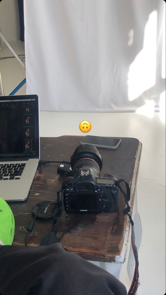 an open laptop computer sitting on top of a wooden table next to a white camera