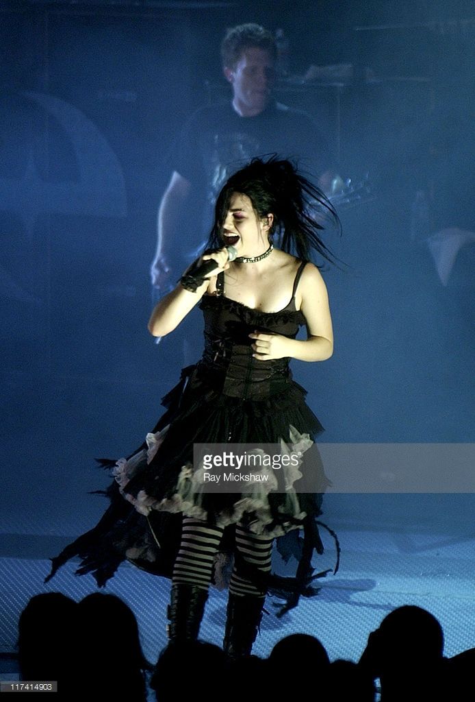 a woman in black dress on stage with microphone