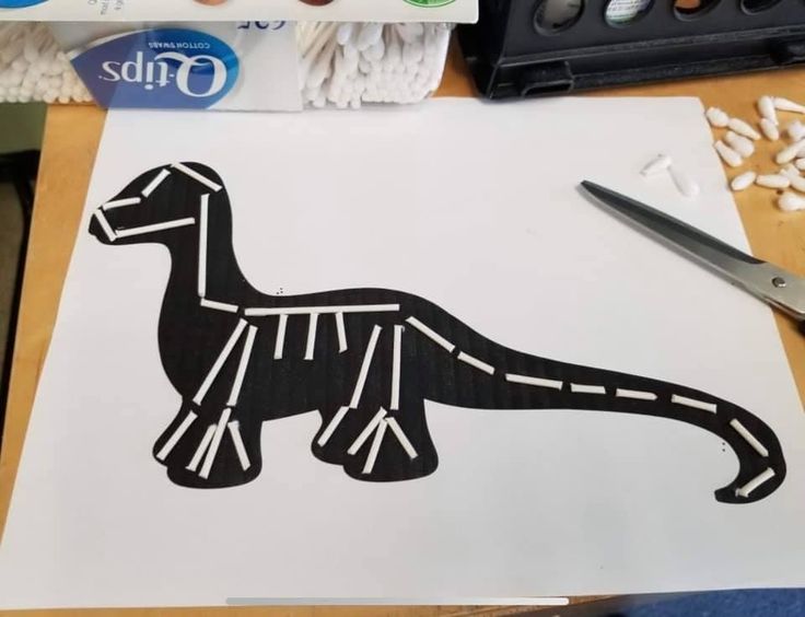 a paper cut out of a dinosaur sitting on top of a table next to scissors