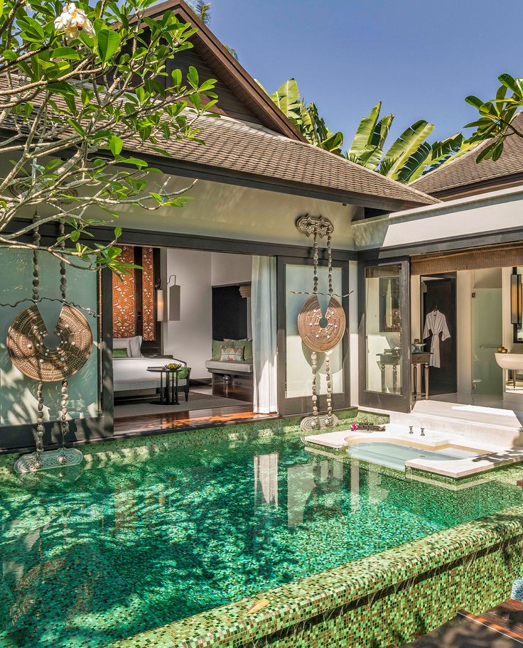 an outdoor pool in front of a house with trees and grass on the ground, surrounded by greenery