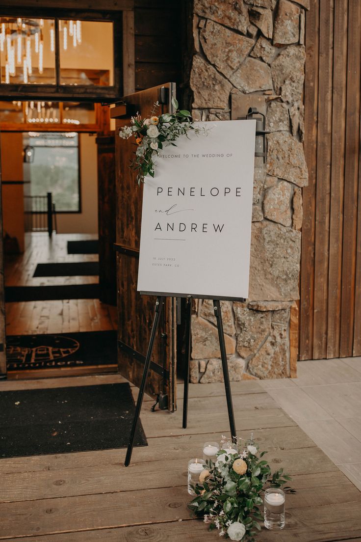 a sign sitting on top of a wooden floor in front of a stone building with candles