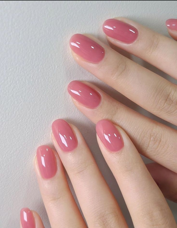 a woman's hand with pink nail polish on her nails, holding onto the tip of her finger