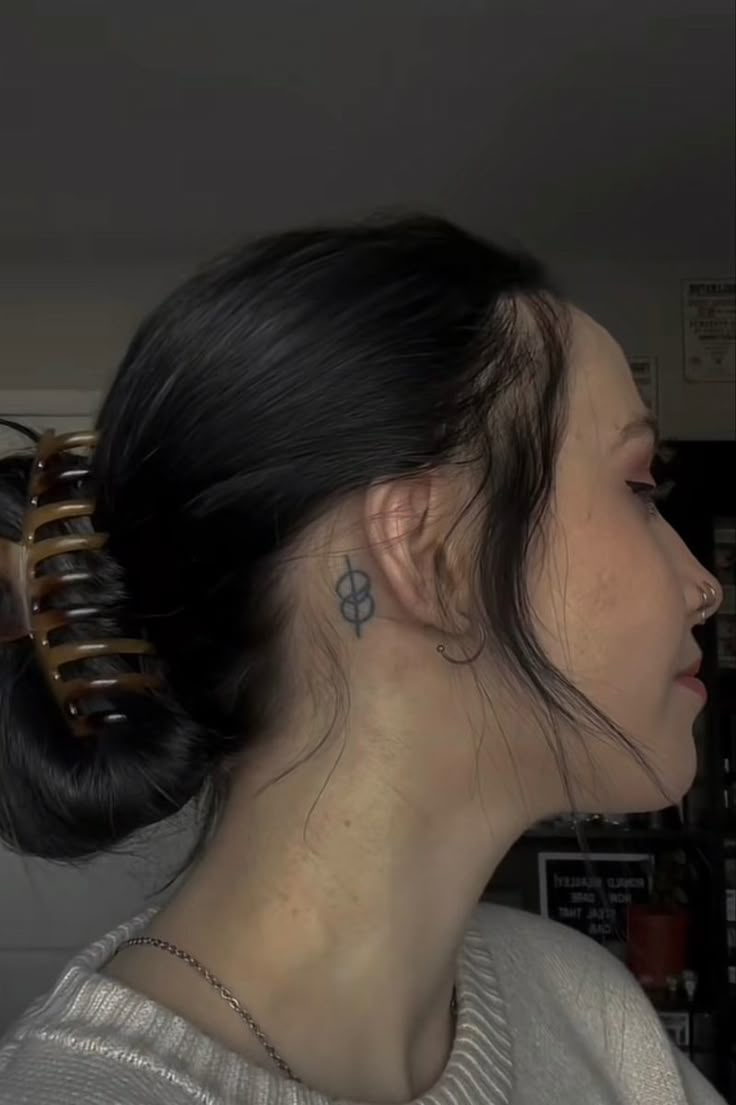 a woman with a tattoo on her left side of her neck and behind her ear