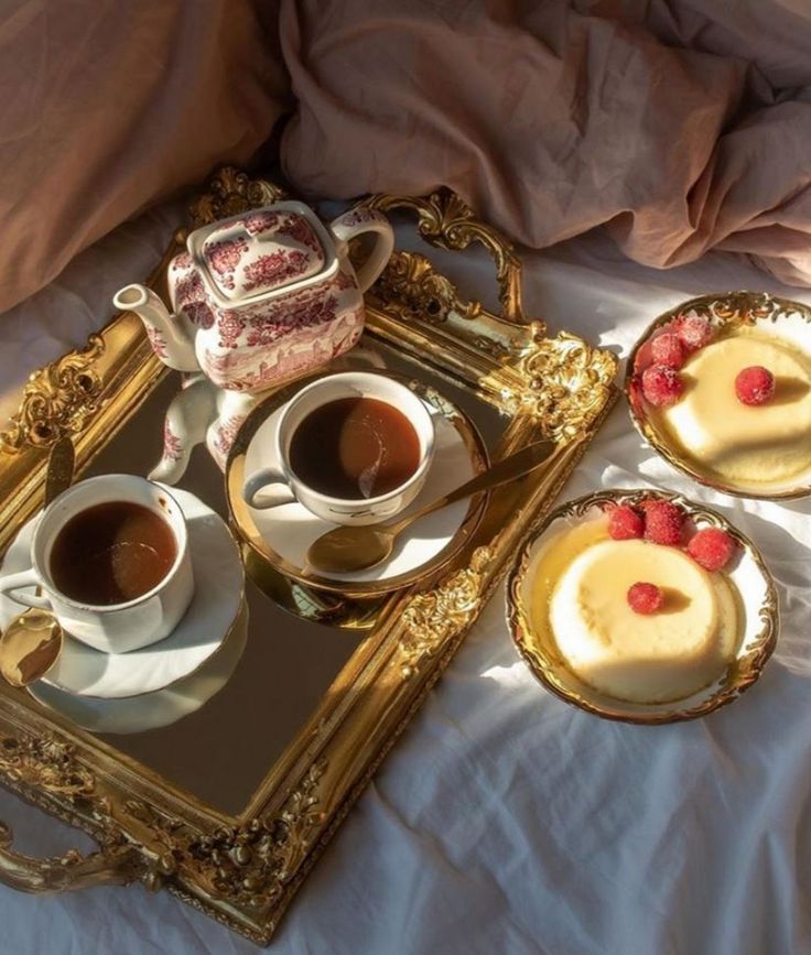 three desserts are sitting on a tray next to a cup of coffee and a teapot