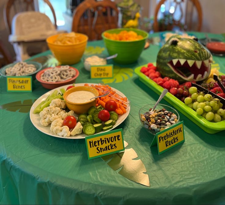 a table topped with plates of food covered in fruit and veggies next to watermelon