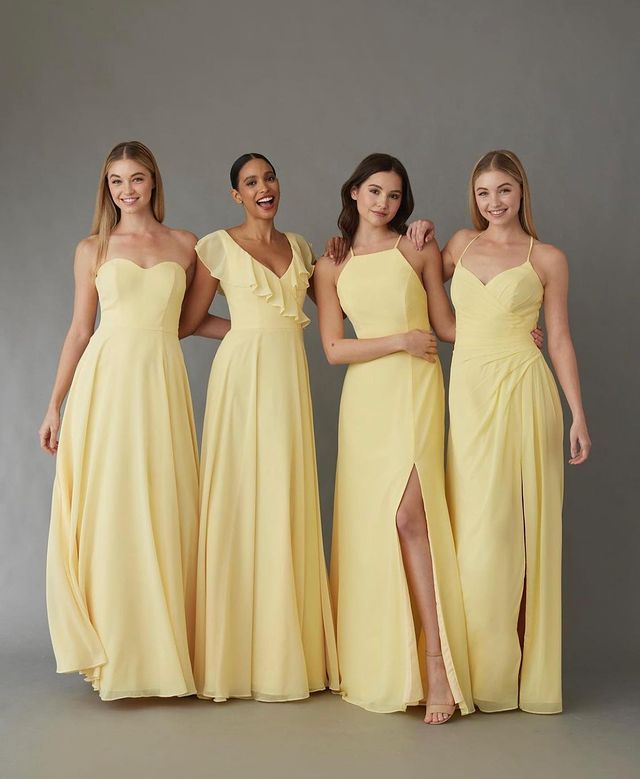 three bridesmaids in yellow dresses posing for the camera with one wearing a high slit dress