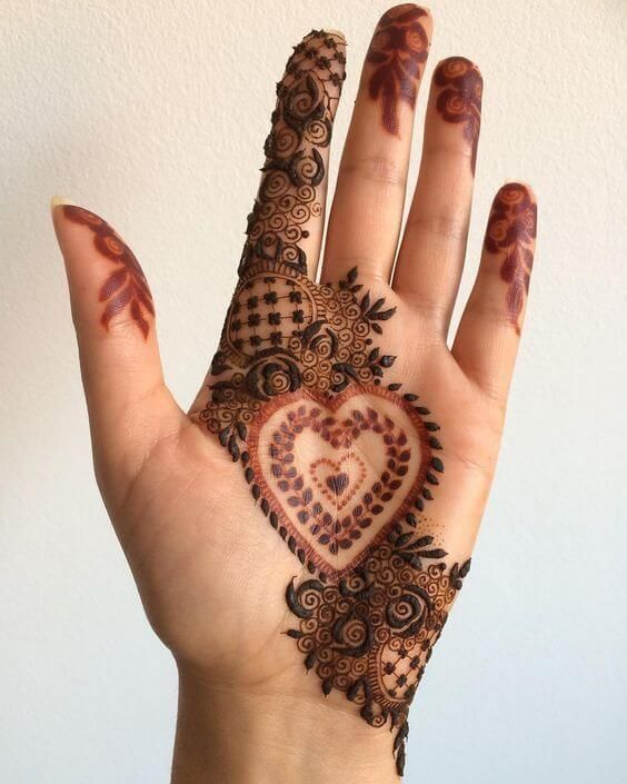 a woman's hand with henna tattoos on it and a heart painted on the palm