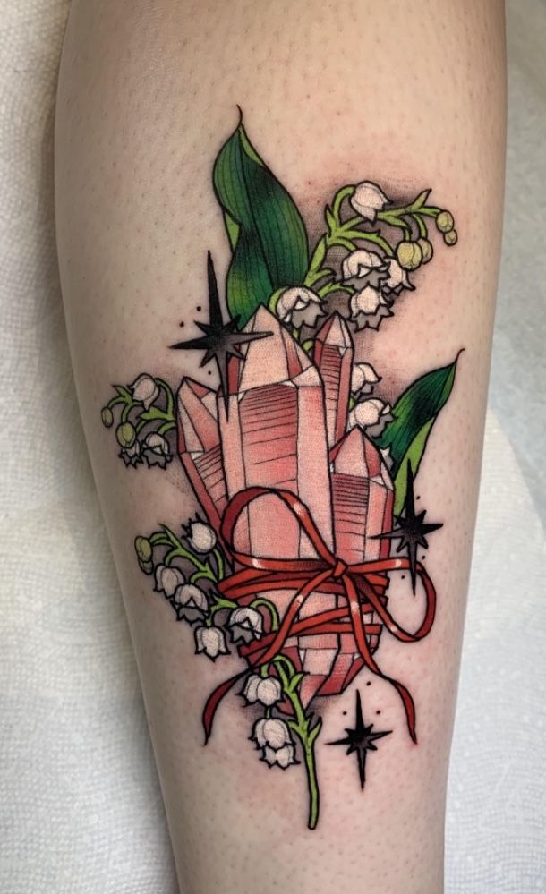 a woman's leg with a tattoo on it and flowers in the center, including lily of the valley