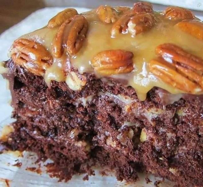 a close up of a piece of cake on a plate with pecans and icing