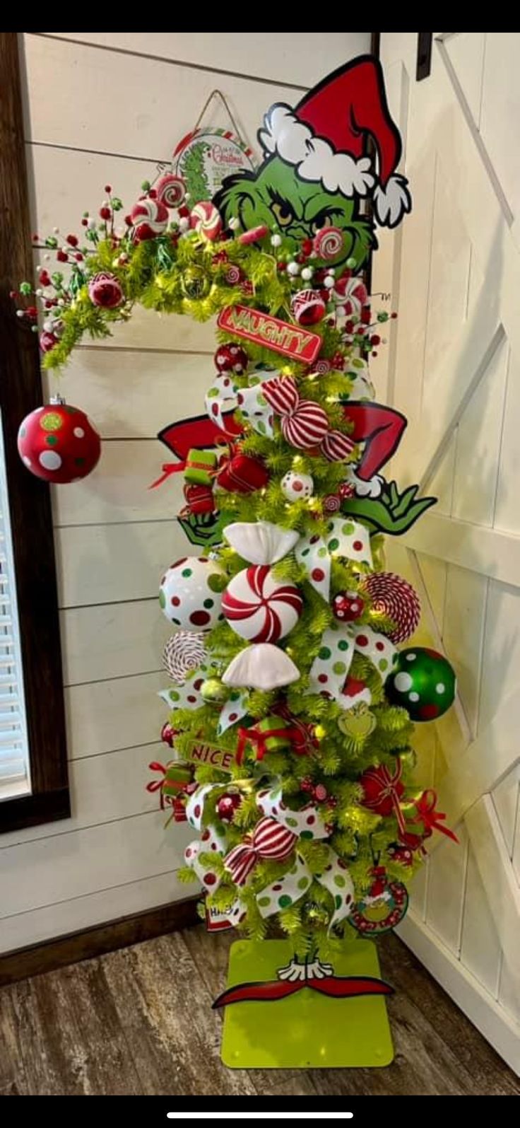 a green christmas tree decorated with candy canes and ornaments in the shape of santa's hat