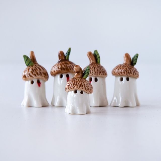 five small white figurines with brown mushrooms on their heads are lined up in a row