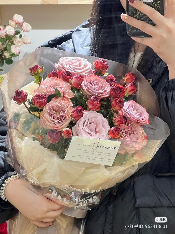 a woman holding a bouquet of pink and red roses