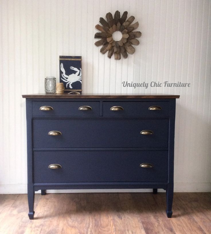 a blue dresser with brass handles and knobs on it's drawers in a room