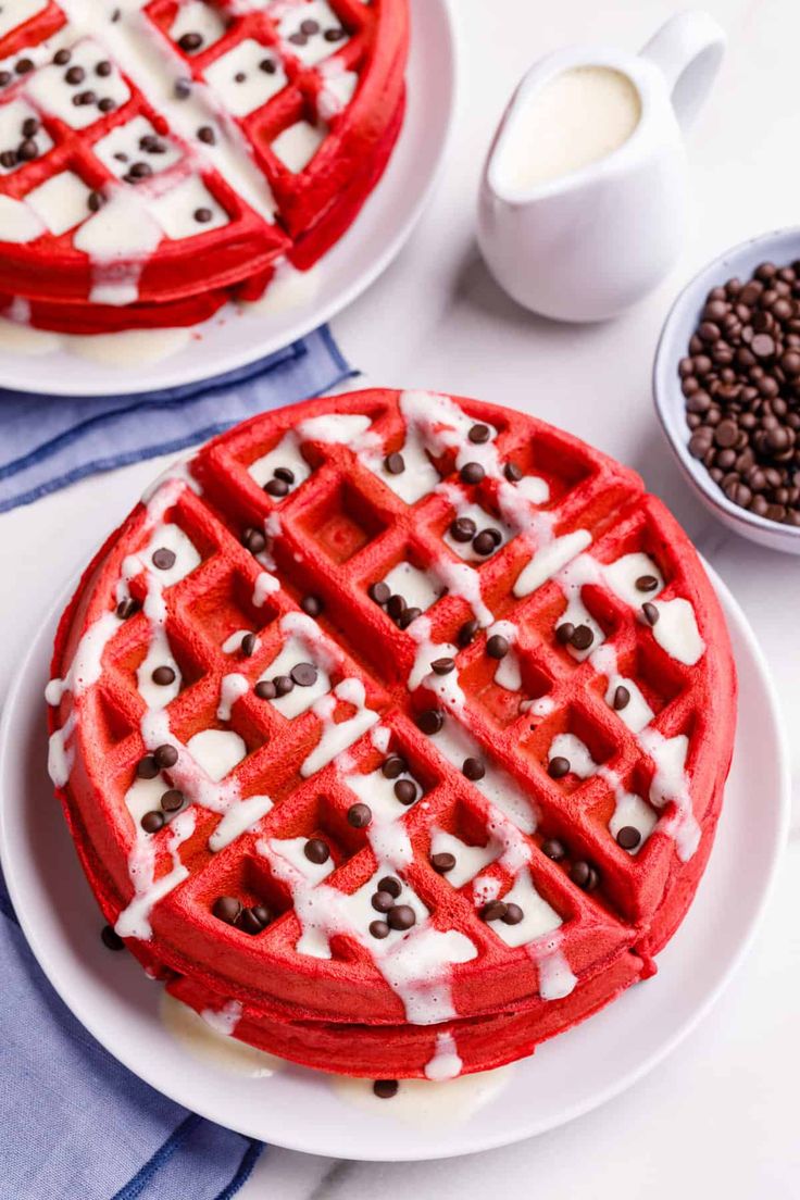 two waffles with chocolate chips on them sitting on plates next to coffee beans