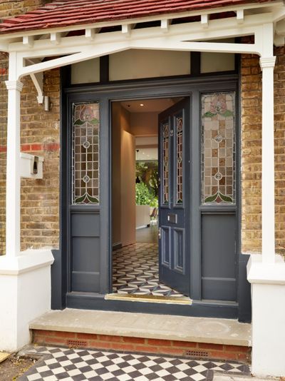 an entrance to a house with blue doors and white trim on the front door, black and white checkered floor