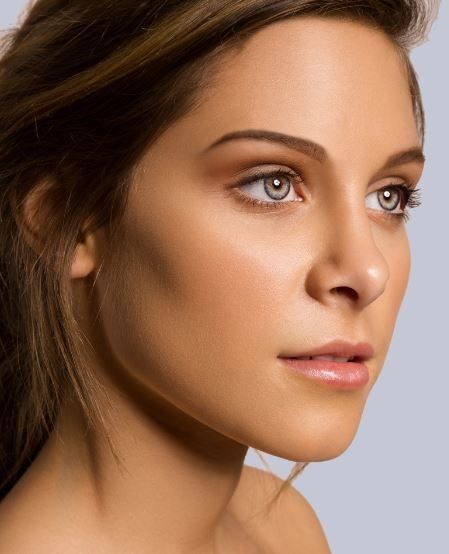 a woman with brown hair and blue eyes is looking at the camera while she has her head tilted to the side