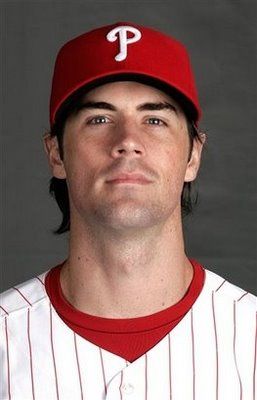 a baseball player in a red and white uniform looking up at the camera with his eyes closed