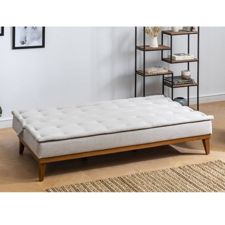 a white couch sitting on top of a wooden floor next to a shelf filled with books