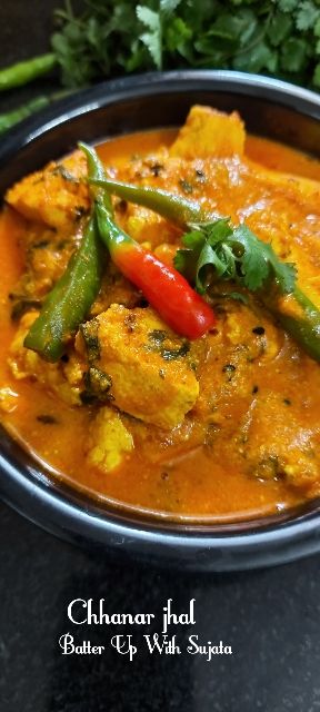 a bowl filled with curry and vegetables on top of a black table next to some parsley