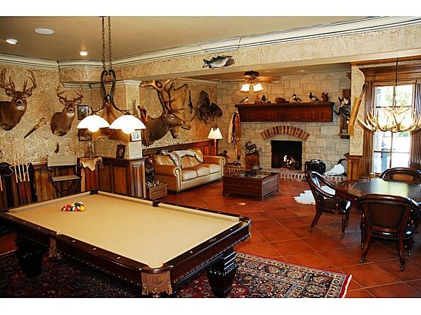 a living room filled with furniture and lots of deer heads mounted to the wall above a pool table