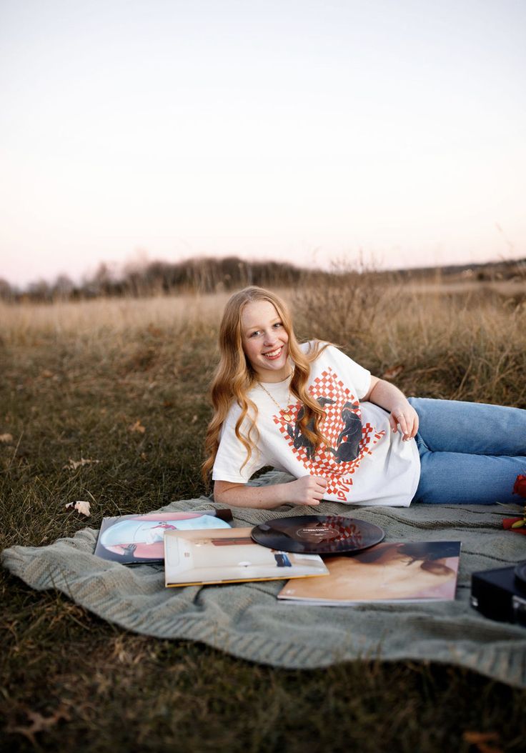 a woman sitting on top of a grass covered field next to a book and camera