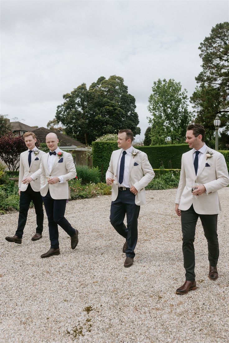 three men in suits and ties standing on gravel