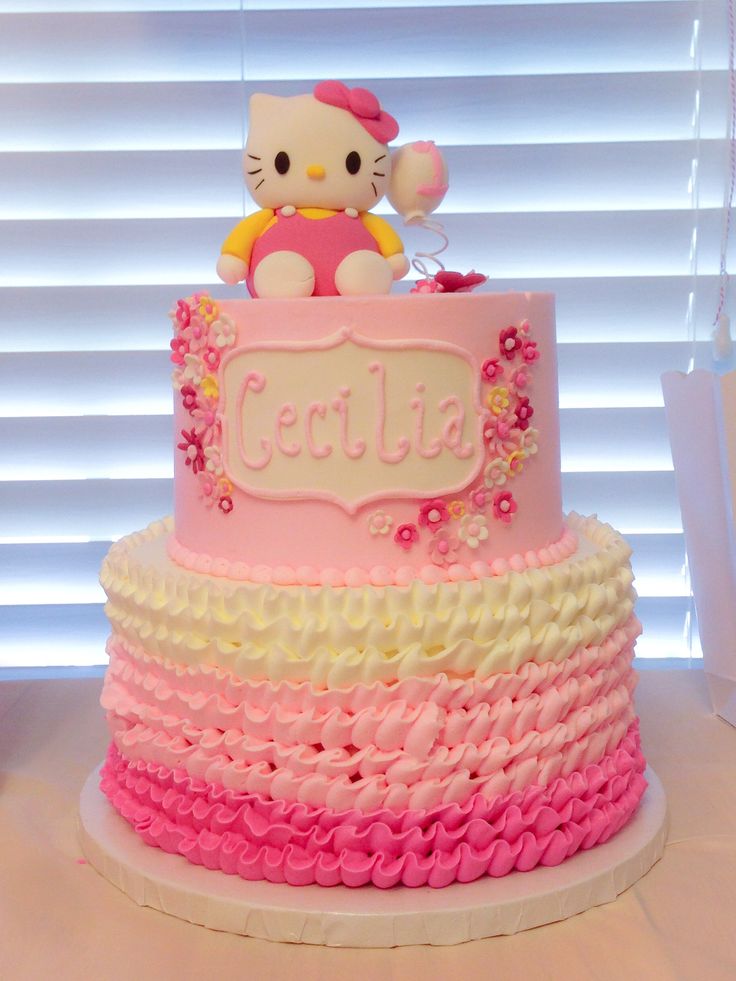 a hello kitty birthday cake with pink, yellow and white icing on it's bottom tier