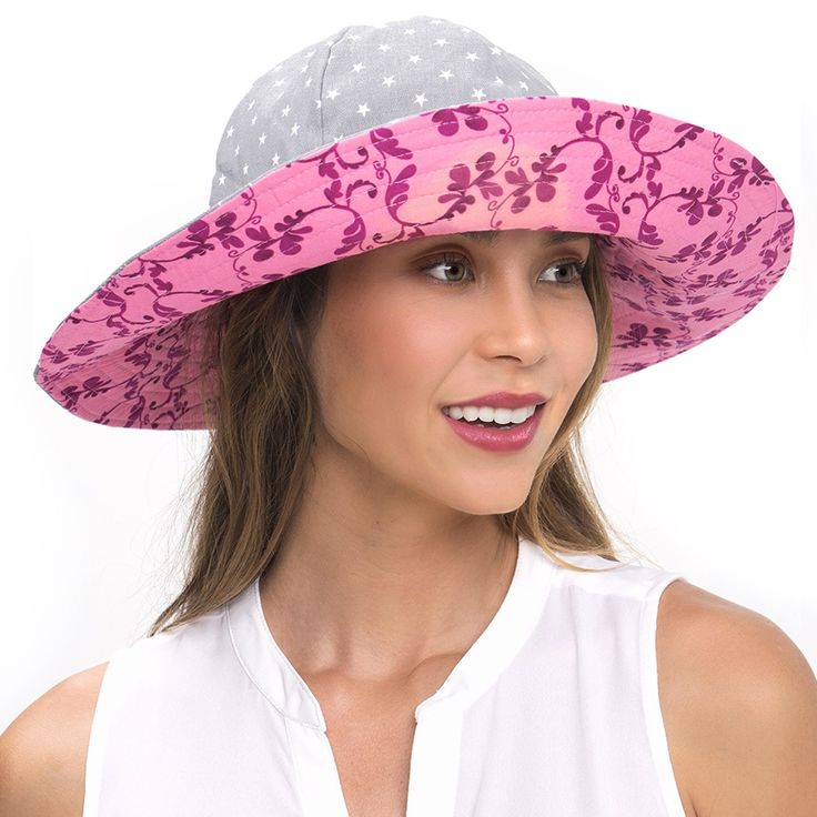 a woman wearing a pink and gray hat with flowers on it's brim