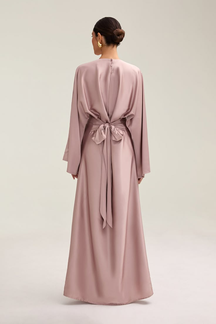 Indulge in luxury with the Batool Satin Maxi Dress. Its loose wide sleeves and lustrous satin fabric exude elegance, while the adjustable tie waist flatters your figure. Versatile design makes it perfect for Eid and beyond. Elevate your style with this exclusive piece. Model is 5'7 wearing size XS/58" Elegant Long Sleeve Dress With Tie Sleeves, Elegant Long Sleeve Dress With Tie Fastening, Chic Wrap Dresses With Tie Back, Chic Wrap Dress With Tie Back, Elegant Wrap Maxi Dress With Tie Waist, Formal Belted Wrap Maxi Dress, Elegant Maxi Dress With Tie Waist And Kimono Sleeves, Elegant Flowy Wrap Dress With Tie Waist, Evening Wrap Maxi Dress With Tie Waist