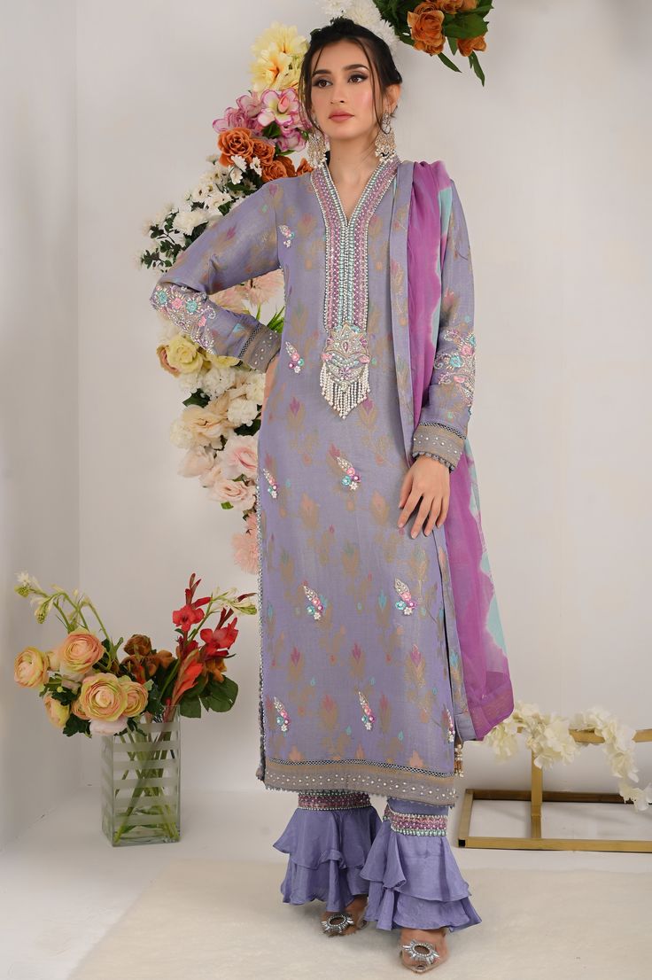 Divine into regal perfection with regal lilac blue. This lilac blue marvel boasts a neckline adorned with vibrant resham, beads and sparkle of sitara, delicately enhanced with beautifully curated bunch on neck line, sleeves and back as well, floral motifs on all over shirt front and intricate resham embroidey and lace work on shirts hem.to complete this ethereal ensemble it is paired with ombre dyed dupatta and two tier ruffled trouser. Shirt Fabric: Pure jacquard maysuri Shirt Length: 48” Pant Designer Embroidered Neckline Dress For Diwali, Festive Anarkali Dupatta With Embroidered Neckline, Wedding Salwar Kameez With Embroidered Neckline For Eid, Eid Wedding Salwar Kameez With Embroidered Neckline, Festive Dupatta With Embroidered Neckline For Eid, Eid Festive Dupatta With Embroidered Neckline, Anarkali Salwar Kameez With Embroidered Neckline For Eid, Bollywood Style Kurta With Embroidered Neckline For Diwali, Traditional Embroidered Salwar Kameez For Wedding