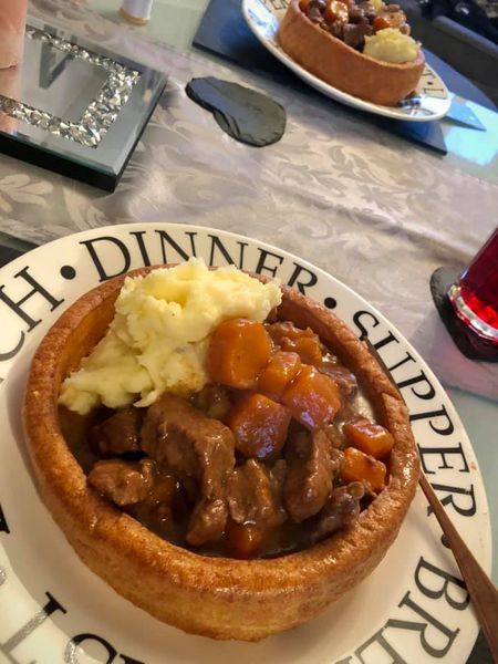 a plate topped with meat and potatoes on top of a table next to a fork