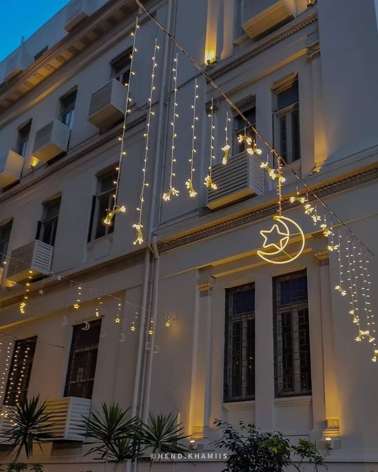 a building with christmas lights hanging from it's windows and on the side of it