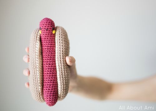 a hand holding a crocheted hot dog bun