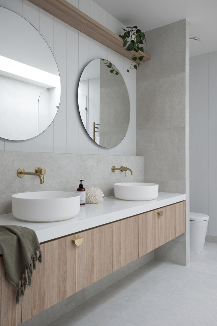 a bathroom with two sinks and mirrors on the wall next to each other in front of a toilet