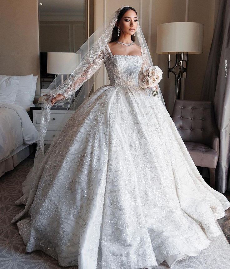 a woman in a white wedding dress standing next to a bed