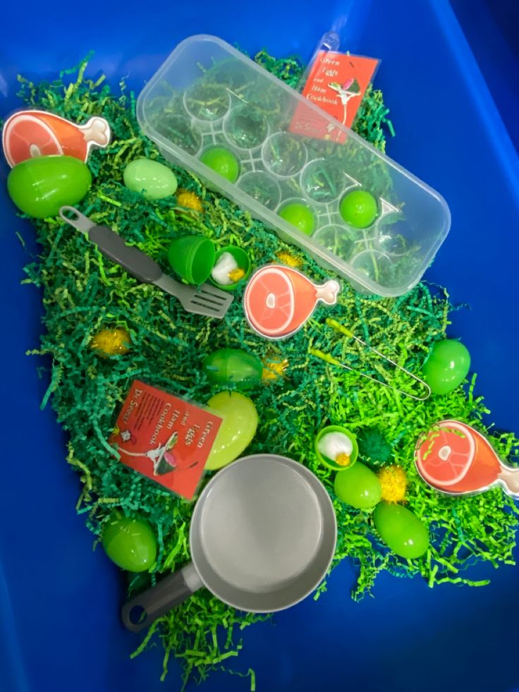 an arrangement of green and orange items in a plastic container on top of fake grass