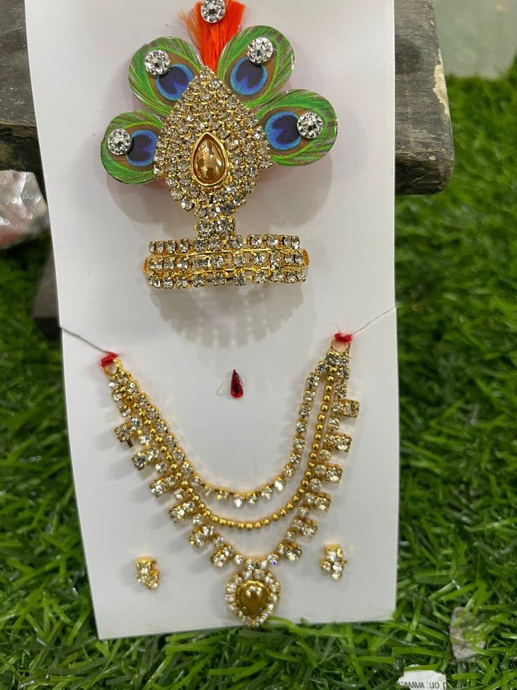 Beautiful multicolour peacock print Mukut with necklace and earrings set for our Krishna ji Available for Laddu Gopal in Size 1 and 2 inches  Size 2 and 3 inches  Size 3 and 4 inches  Can be used for other deity idols Designer piece  Quality guaranteed  From land of Krishna, Mathura Temple Jewelry With Peacock Design For Puja, Peacock Design Temple Jewelry For Puja, Multicolor Peacock Design Necklace For Puja, Spiritual Gold Jewelry Sets For Festivals, Traditional White Jewelry With Peacock Design, White Temple Jewelry Sets As Gift, Spiritual Wedding Jewelry With Peacock Design, White Temple Jewelry Set For Gift, Silver Peacock Design Jewelry For Puja