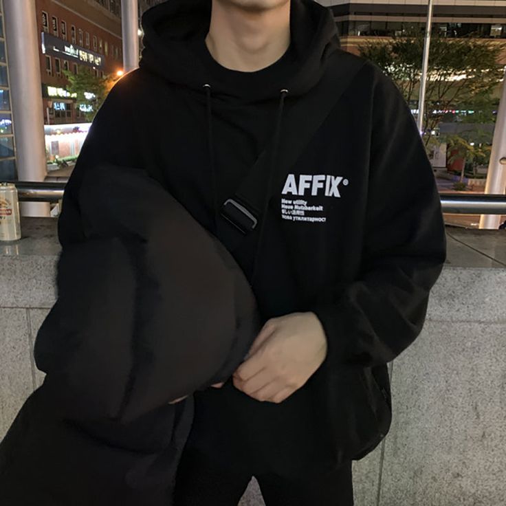 a young man in a black hoodie is standing outside