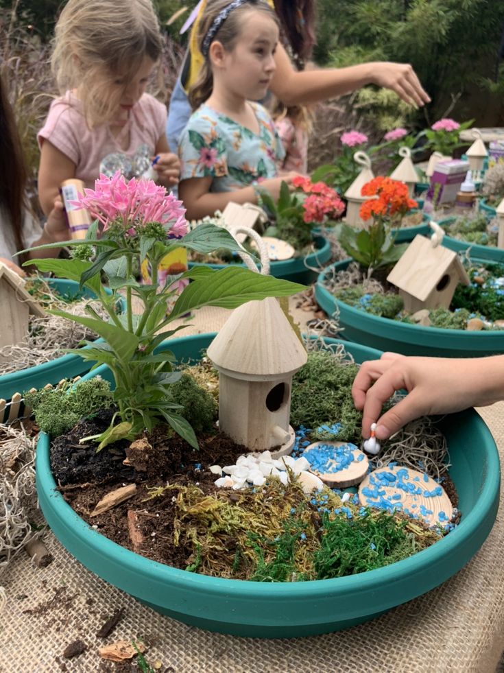 children are playing with miniature fairy houses and plants