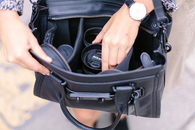 a woman holding a black purse with her hands in it