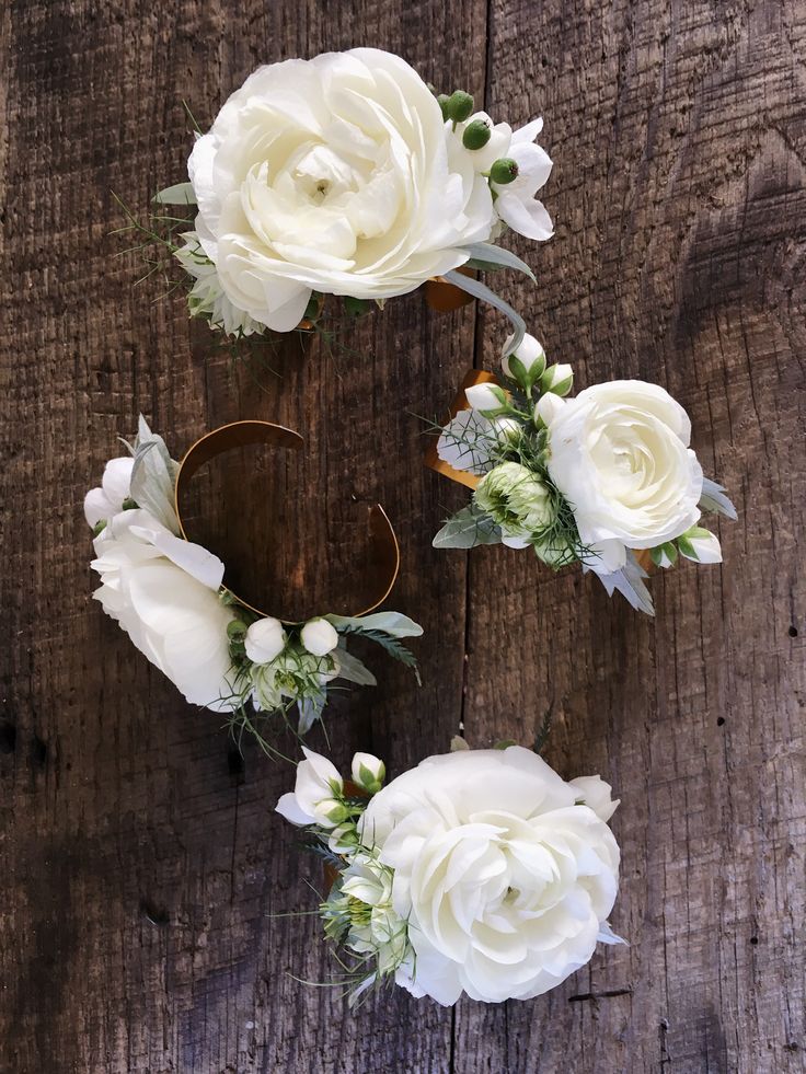 white flowers and greenery are arranged on a wooden surface