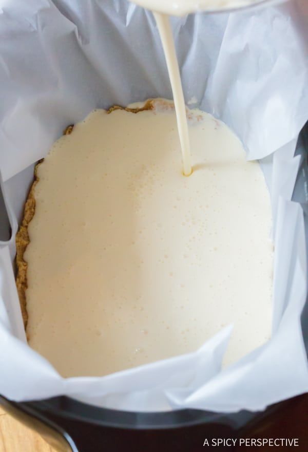 a person pouring milk on top of a cake in a paper bag next to a knife