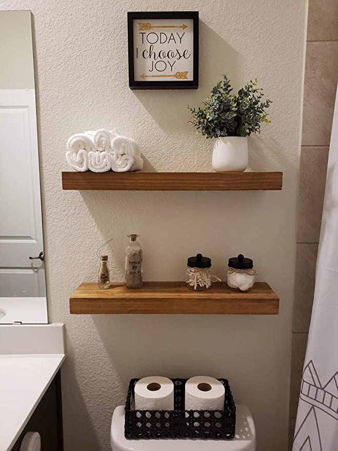 a bathroom with two floating shelves above the toilet