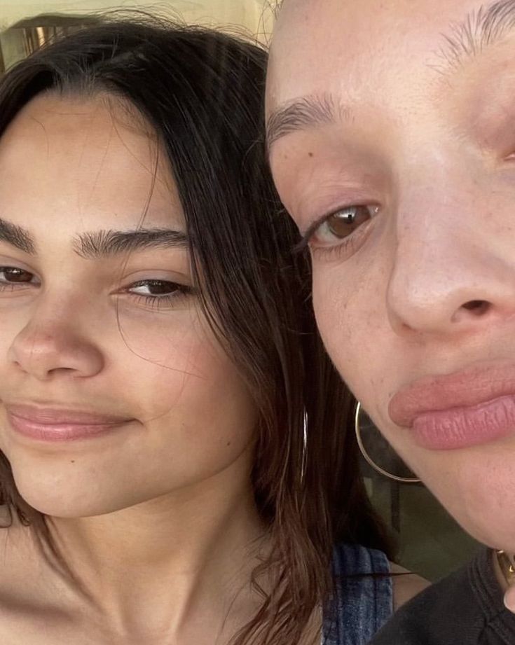 two women are posing for the camera with their heads close to each other and one woman has her hair pulled back