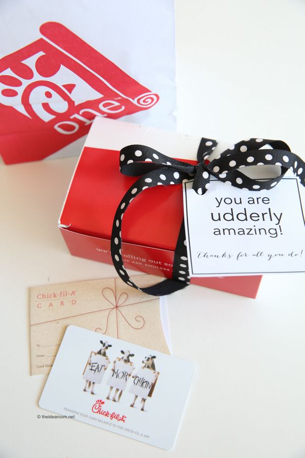 an open red gift box with a black bow and polka dot ribbon on it next to some cards