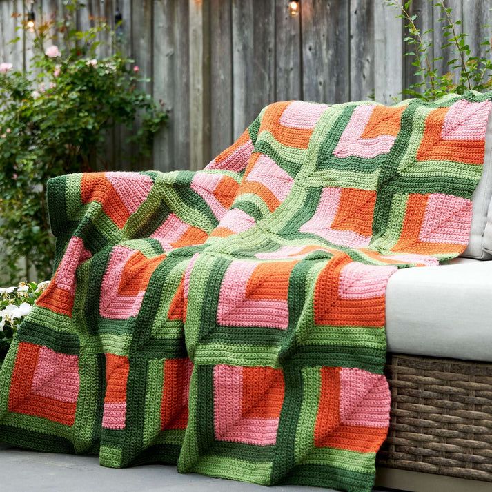 a crocheted blanket sitting on top of a bench