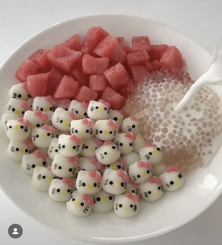 a white plate topped with lots of cut up watermelon and marshmallows