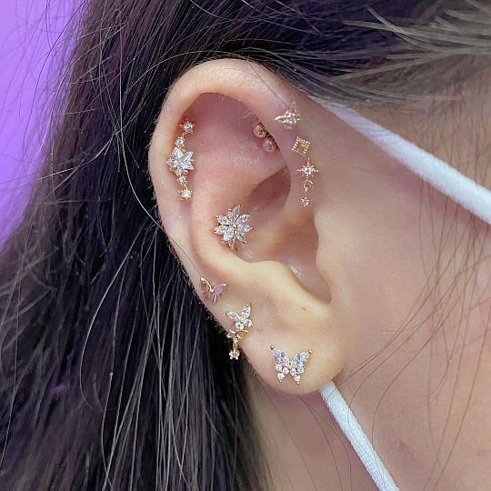 a close up of a person with ear piercings on their ears and behind the ear