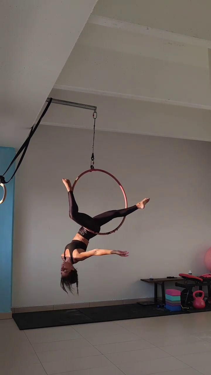 a woman doing aerial acrobatics on a hoop in a room with other equipment