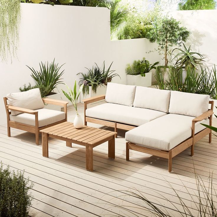 a couch and table on a deck with potted plants